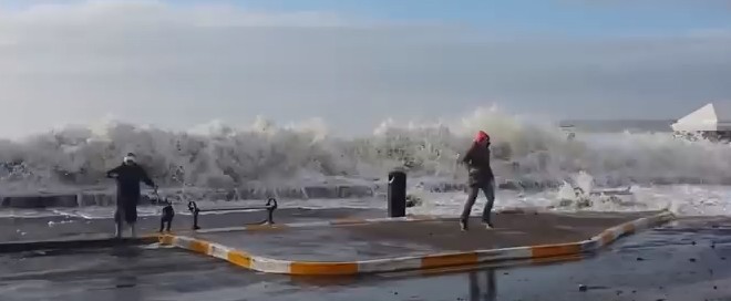Une femme se fait surprendre par une vague en promenant son chien