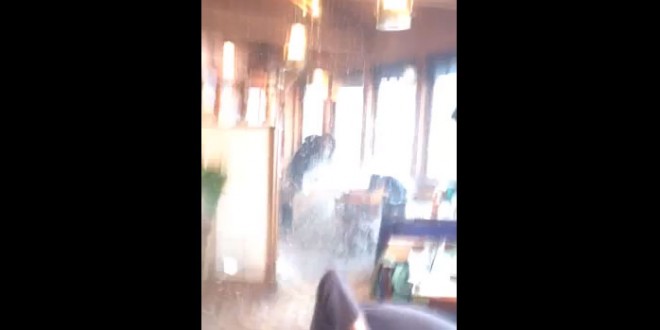 Une vague brise la vitre d’un restaurant